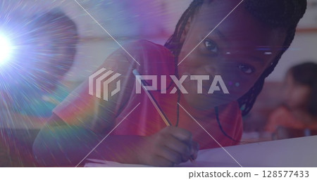 Image of light trails over african american schoolgirl in classroom 128577433