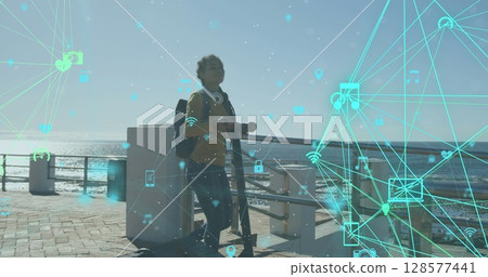 Image of media icons over biracial woman walking with scooter on promenade 128577441