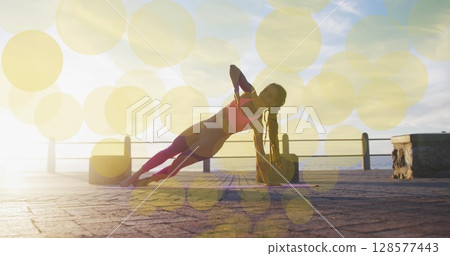 Image of yellow spots over biracial woman exercising on promenade 128577443