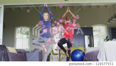 Image of heart icons over senior diverse couple practicing yoga at home 128577551