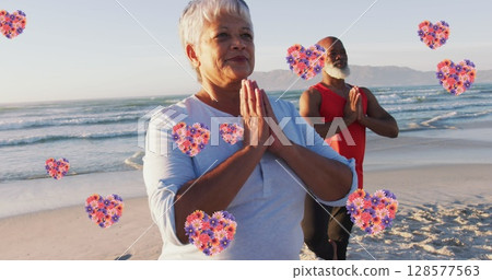 Image of heart icons over senior african american couple practicing yoga at beach 128577563