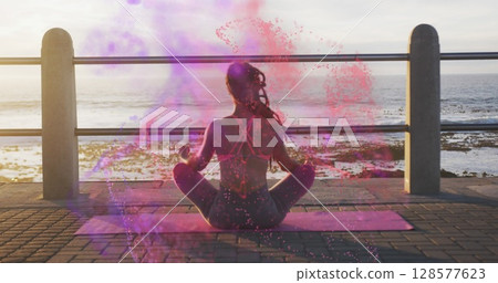 Image of colourful spots over biracial woman meditating by sea 128577623