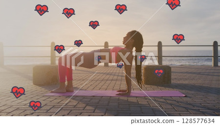 Image of heart icons over biracial woman exercising on promenade 128577634