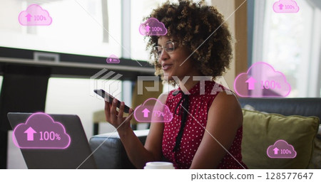 Image of clouds icons over african american businesswoman using smartphone 128577647