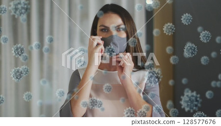 Image of virus cells over caucasian woman with face mask Image of virus cells over caucasian woman with face mask 128577676