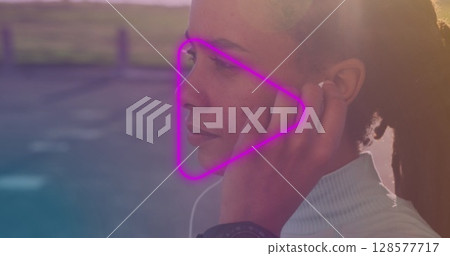 Neon purple play icon against close up of african american woman wearing earphones 128577717