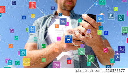 Image of network of connections with icons over caucasian man using smartphone outdoors 128577877
