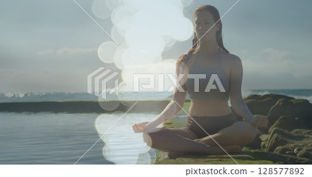 Image of light spots over caucasian woman practicing yoga and meditating Image of light spots over caucasian woman practicing yoga and meditating 128577892