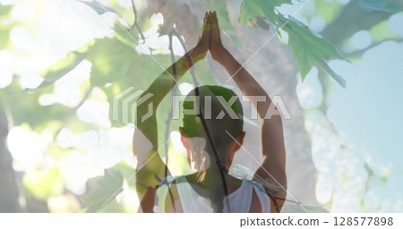 Image of leaves over caucasian woman practicing yoga and meditating 128577898