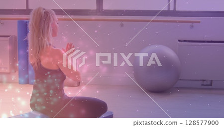 Image of light spots over caucasian woman practicing yoga and meditating 128577900