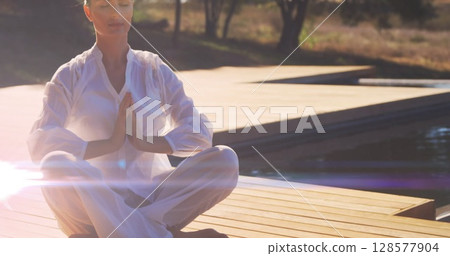 Image of light spots over caucasian woman practicing yoga and meditating Image of light spots over caucasian woman practicing yoga and meditating 128577904