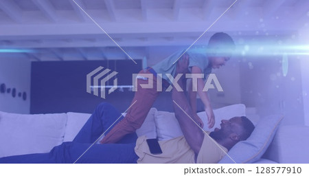 Image of lights over happy african american father and son having fun on sofa Image of lights over happy african american father and son having fun on sofa 128577910