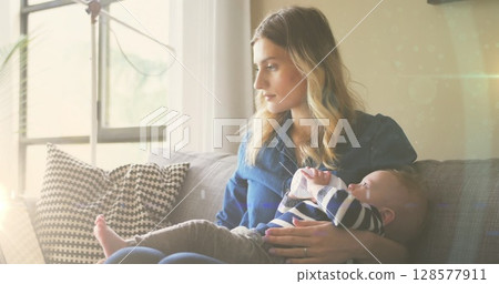Image of glowing spots over caucasian mother with baby with drinking milk 128577911