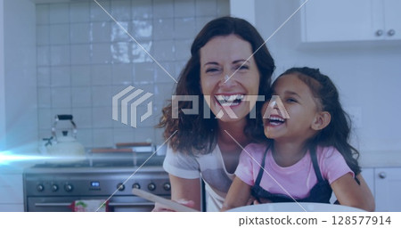 Image of glowing spots over happy biracial mother with daughter baking together 128577914