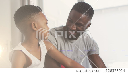 Image of lights over happy african american father helping son to tie shoe Image of lights over happy african american father helping son to tie shoe 128577924