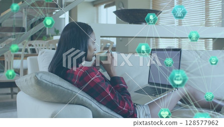 Image of network of connections with icons over biracial woman using laptop Image of network of connections with icons over biracial woman using laptop 128577962