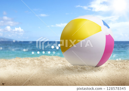 Colorful beach ball on a beautiful sandy beach with an ocean view and a blue sky background. Summer concept Colorful beach ball on a beautiful sandy beach with an ocean view and a blue sky background. Summer concept 128578345