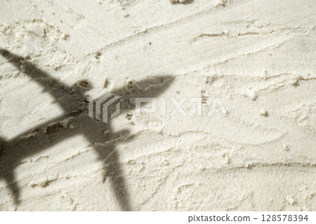 Shadow of an airplane flies over a beautiful sandy beach. Natural background. Summer concept. Top view Shadow of an airplane flies over a beautiful sandy beach. Natural background. Summer concept. Top view 128578394