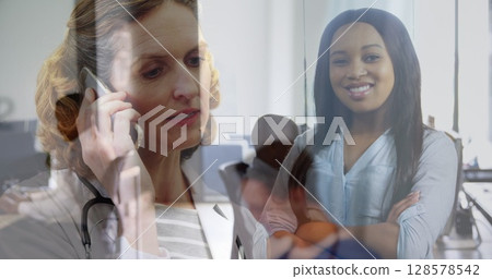 Image of caucasian woman having call over biracial businesswoman in office Image of caucasian woman having call over biracial businesswoman in office 128578542