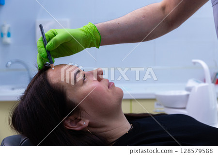 Expert Preparation for Cosmetic Procedure: Professional Applying Markings with Precision to Enhance Client's Natural Features in Modern Aesthetic Environment Expert Preparation for Cosmetic Procedure: Professional Applying Markings with Precision to Enhance Client's Natural Features in Modern Aesthetic Environment 128579588