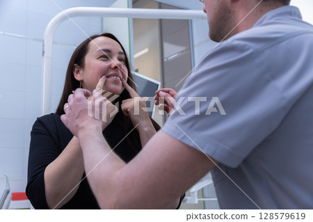 A Gentle Interaction: A Patient Engaging with a Professional in a Dental or Medical Environment, Highlighting the Importance of Patient-Care Relationship and Communication Skills. A Gentle Interaction: A Patient Engaging with a Professional in a Dental or Medical Environment, Highlighting the Importance of Patient-Care Relationship and Communication Skills. 128579619