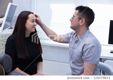 A Professional Consultation in a Modern Dental Clinic: Dentist Explains Procedure to Patient with Care and Focus in a Bright, Clean Setting A Professional Consultation in a Modern Dental Clinic: Dentist Explains Procedure to Patient with Care and Focus in a Bright, Clean Setting 128579631