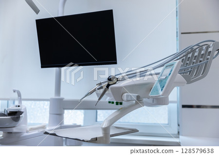 Modern Dental Chair and Equipment in a Bright Dental Clinic Setting with an LCD Monitor and Tools Ready for Patient Care Modern Dental Chair and Equipment in a Bright Dental Clinic Setting with an LCD Monitor and Tools Ready for Patient Care 128579638