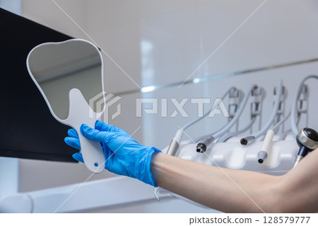 Reflection of Dental Care: A Close-Up on a Dentist's Mirror in a Modern Clinic Setting with Essential Dental Tools in the Background 128579777
