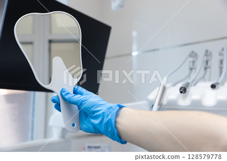 Presentation of a Dental Mirror in a Modern Clinic Setting: Essential Tool for Dental Professionals to Conduct Thorough Oral Examinations and Patient Care 128579778