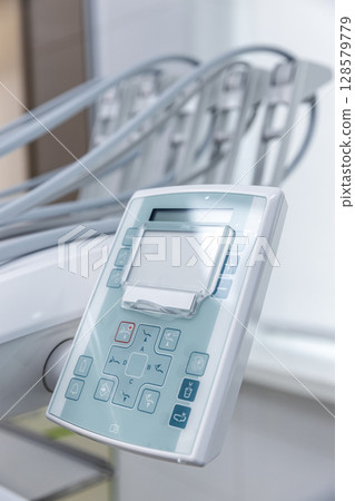 Modern Dental Equipment Control Panel with Various Functions for Patient Comfort and Efficient Dental Procedures in a Bright Clinical Environment 128579779