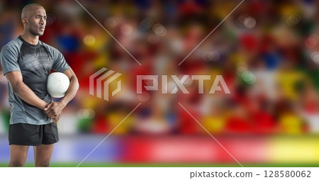 Male athlete is standing on grass pitch, holding white soccer ball in flat design sports scene 128580062