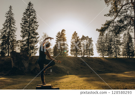 Fit sporty happy young woman wearing sportswear meditating doing yoga breathing stretching exercises standing in nature park outdoors in sunny morning. Authentic candid photo. Fit sporty happy young woman wearing sportswear meditating doing yoga breathing stretching exercises standing in nature park outdoors in sunny morning. Authentic candid photo. 128580293