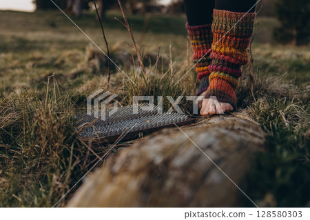 Bare feet in knitted leg warmers standing on nails over grass, symbolizing yoga practice, meditation, pain tolerance, and overcoming fear. A powerful image of mental strength and body awareness 128580303