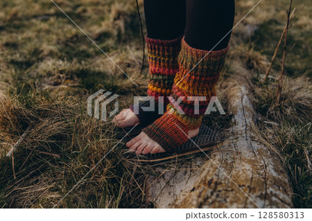 Bare feet in knitted leg warmers standing on nails over grass, symbolizing yoga practice, meditation, pain tolerance, and overcoming fear. A powerful image of mental strength and body awareness Bare feet in knitted leg warmers standing on nails over grass, symbolizing yoga practice, meditation, pain tolerance, and overcoming fear. A powerful image of mental strength and body awareness 128580313