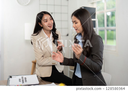 Engaging Conversation. Two businesswomen discussing ideas and strategies in a modern office. Engaging Conversation. Two businesswomen discussing ideas and strategies in a modern office. 128580364