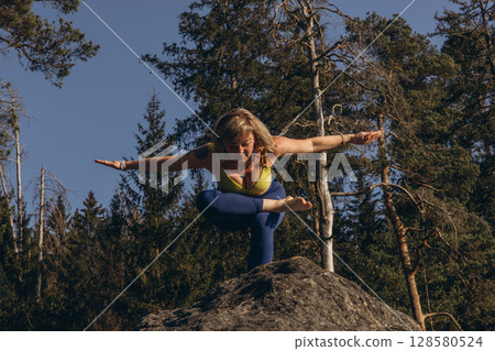 A woman meditating and practicing yoga on top of a rock at sunset, embracing wellness, mindfulness, and eco-friendly living A woman meditating and practicing yoga on top of a rock at sunset, embracing wellness, mindfulness, and eco-friendly living 128580524