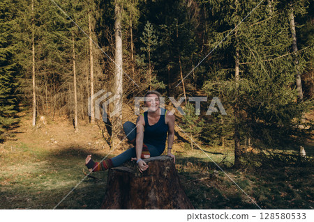 Fit sporty happy young woman wearing sportswear meditating doing yoga breathing stretching exercises standing in nature park outdoors in sunny morning. Authentic candid photo. Fit sporty happy young woman wearing sportswear meditating doing yoga breathing stretching exercises standing in nature park outdoors in sunny morning. Authentic candid photo. 128580533