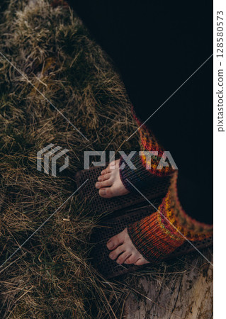 Bare feet in knitted leg warmers standing on nails over grass, symbolizing yoga practice, meditation, pain tolerance, and overcoming fear. A powerful image of mental strength and body awareness Bare feet in knitted leg warmers standing on nails over grass, symbolizing yoga practice, meditation, pain tolerance, and overcoming fear. A powerful image of mental strength and body awareness 128580573