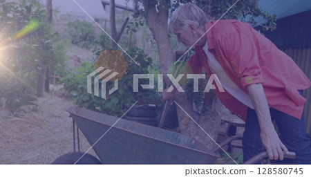 Image of glowing spots of light over caucasian man with wheelbarrow gardening 128580745