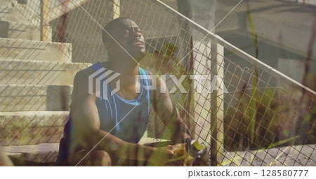 Image of grass over exercising african american man taking a water break sitting in sun Image of grass over exercising african american man taking a water break sitting in sun 128580777