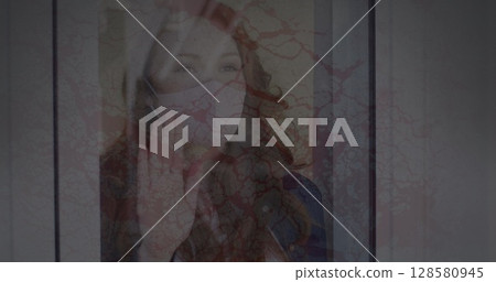 Image of cracked texture changing over sad biracial woman in face mask looking outside window Image of cracked texture changing over sad biracial woman in face mask looking outside window 128580945