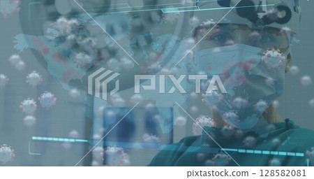 Standing surgeon wearing surgical mask cap scrubs monitoring digital graphics in OR, copy space 128582081