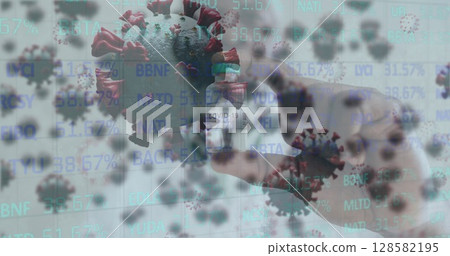 Mature male hand holding COVID-19 vaccine vial in studio with virus particles and data overlays 128582195
