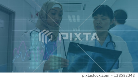 Image of financial graphs and data over diverse female doctors with x ray photo Image of financial graphs and data over diverse female doctors with x ray photo 128582348