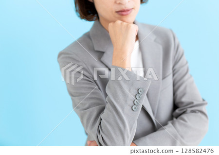 A middle-aged business woman wearing a suit and thinking 128582476