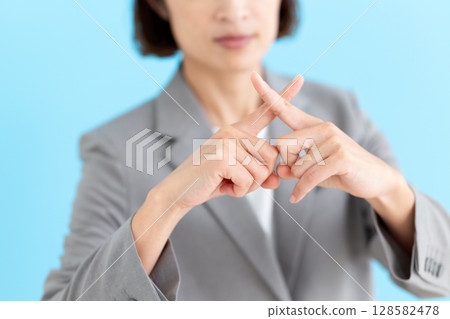 A middle-aged female business woman wearing a suit making a cross sign A middle-aged female business woman wearing a suit making a cross sign 128582478