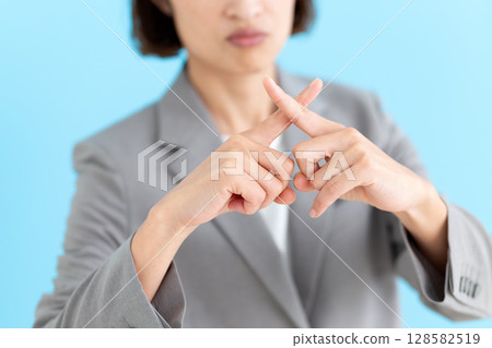 A middle-aged female business woman wearing a suit making a cross sign A middle-aged female business woman wearing a suit making a cross sign 128582519
