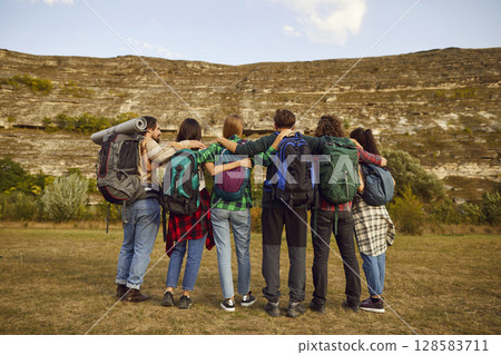 Friends tourists with backpacks standing outdoor and looking to the mountains enjoying nature. Friends tourists with backpacks standing outdoor and looking to the mountains enjoying nature. 128583711