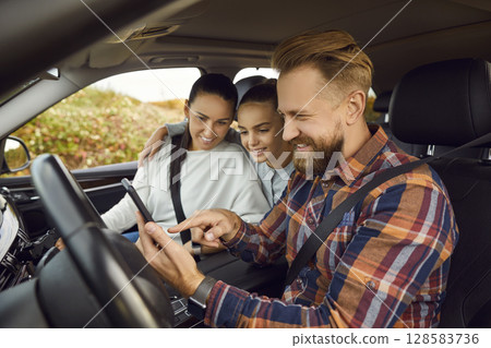 Happy family sitting inside car using digital map application and showing way. Road trip concept. Happy family sitting inside car using digital map application and showing way. Road trip concept. 128583736
