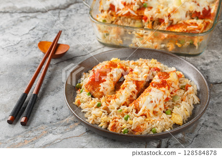 Hong Kong food baked pork chop with fried rice, tomato sauce and melted cheese on top close-up in plate on table. Horizontal 128584878
